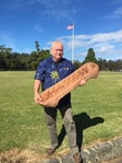 Bill holding a handcrafted wooden paddle outdoors
