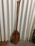 Tall wooden paddle against white curtain
